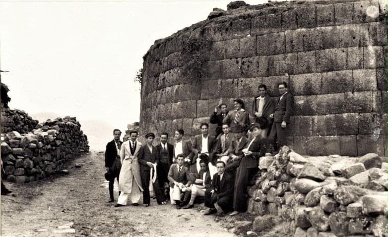 Grupo de personas junto a una construcción de piedra