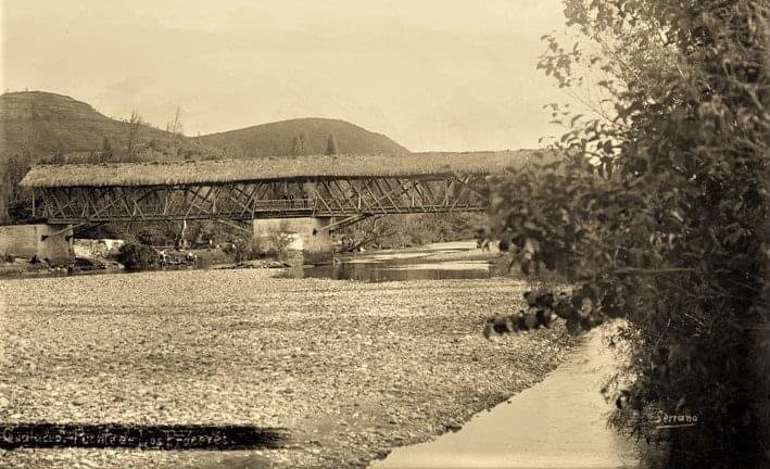 Puente histórico sobre un río rodeado de campos